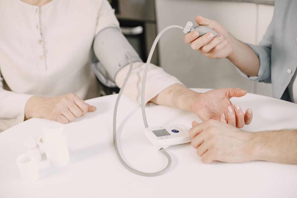 Blood pressure cuff on a woman arm while a second person squeezes the bulb