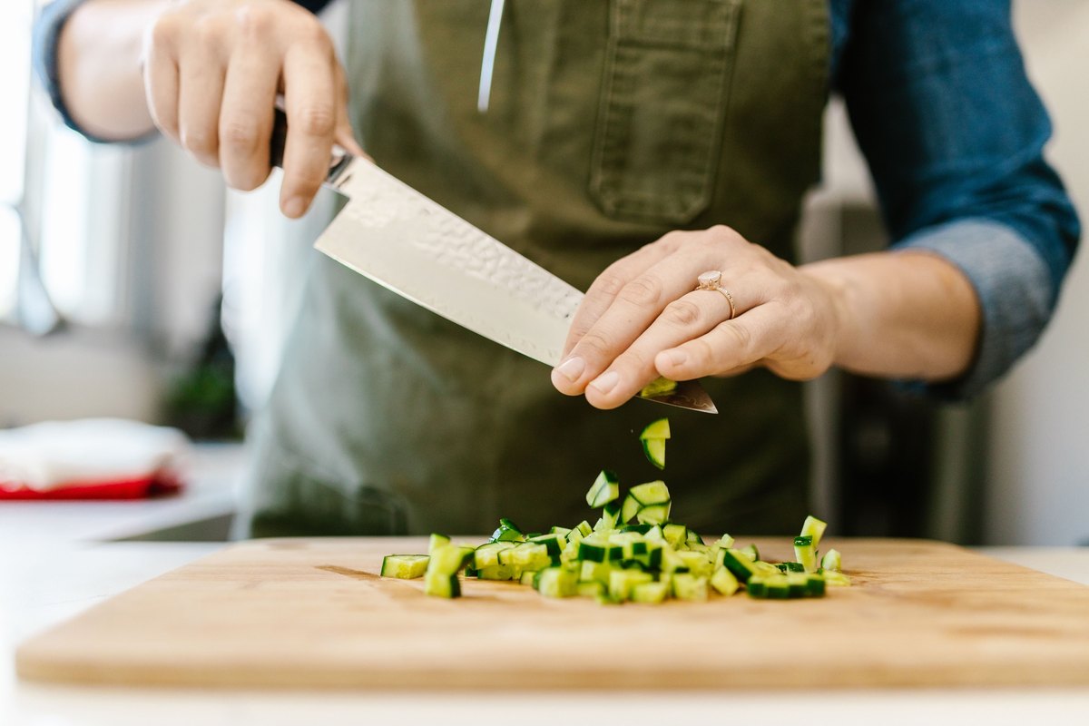 Diced cucumber falling from a chef knife onto a cutting board