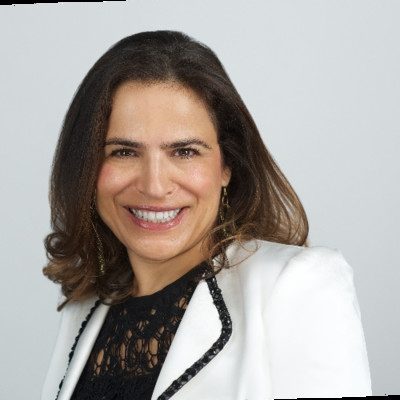Eleni Pellazgu smiling in a white jacket over a black lace top