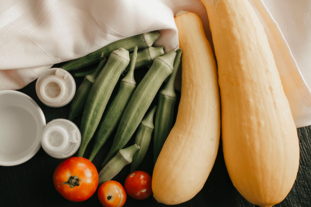 Yellow squash, okra and tomatoes on a dark wood surface
