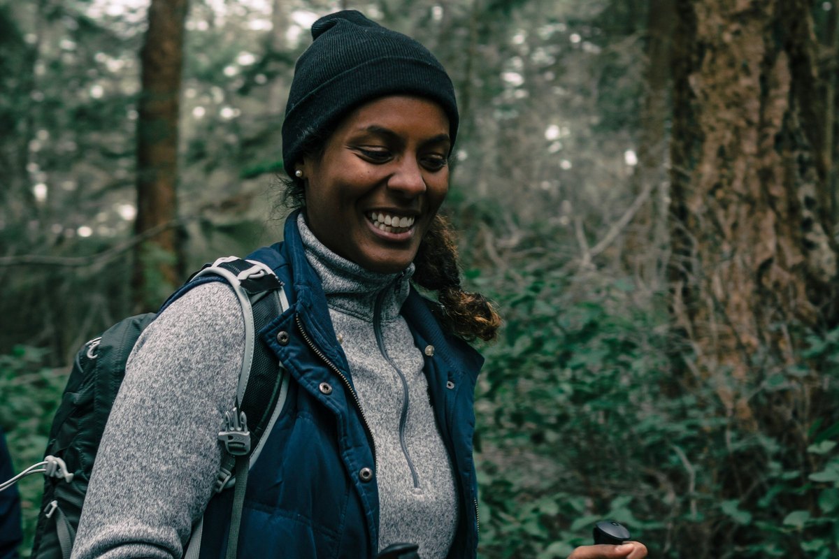 Laughing woman hiking a forest trail with trekking poles