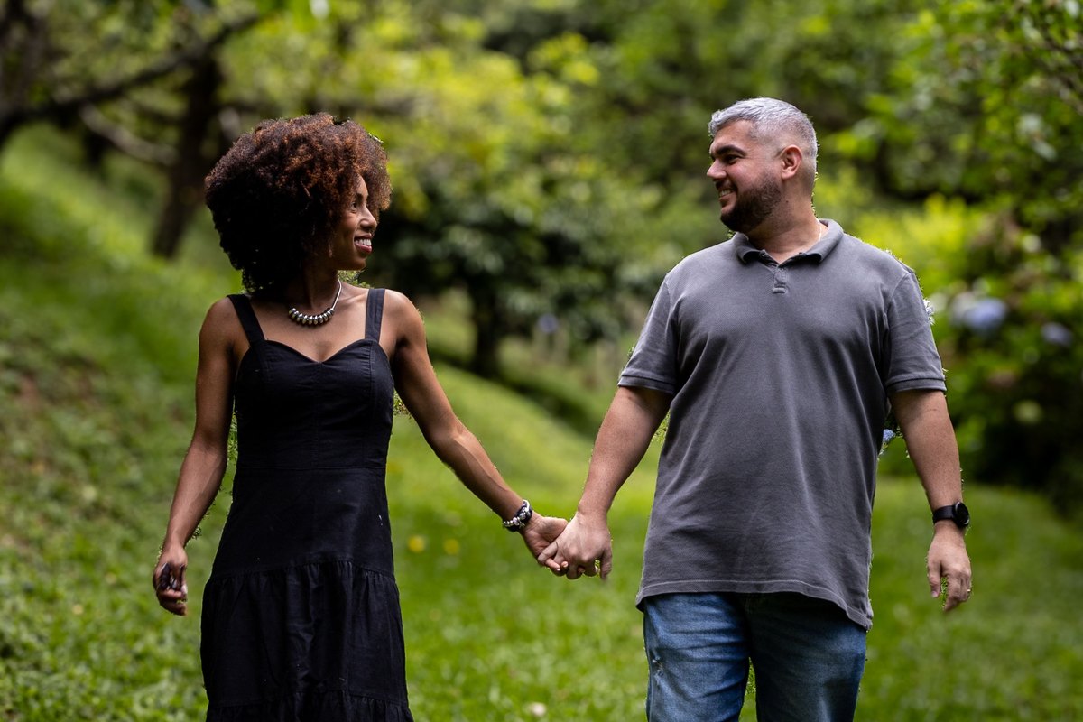 Two adults walking hand in hand beneath leafy trees