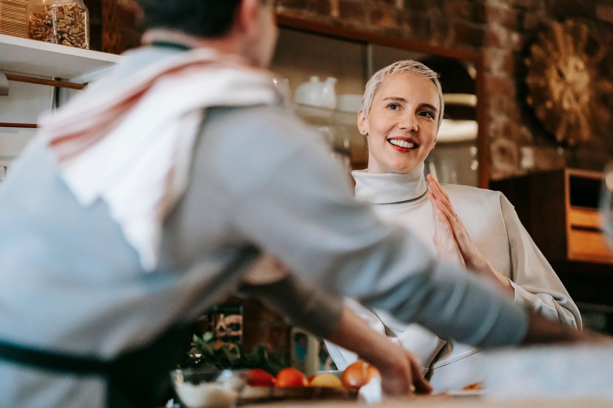 Woman with short platinum hair smiling across a kitchen counter