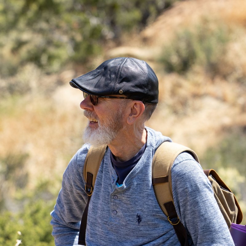 Smiling man with a gray beard and backpack outdoors