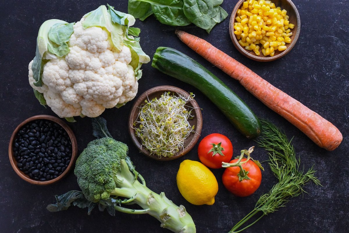 Colorful vegetables, leafy greens and a bowl of beans arranged overhead