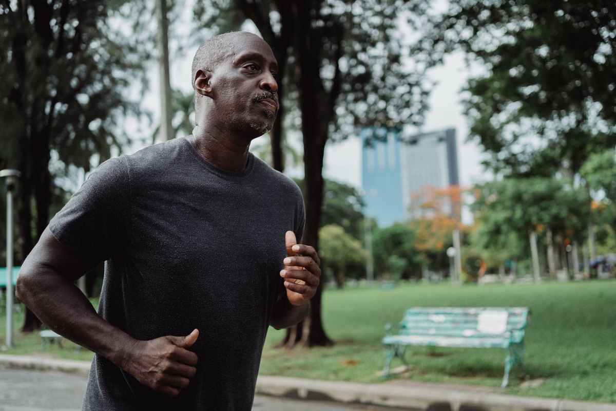 Man with a gray beard running through a city park