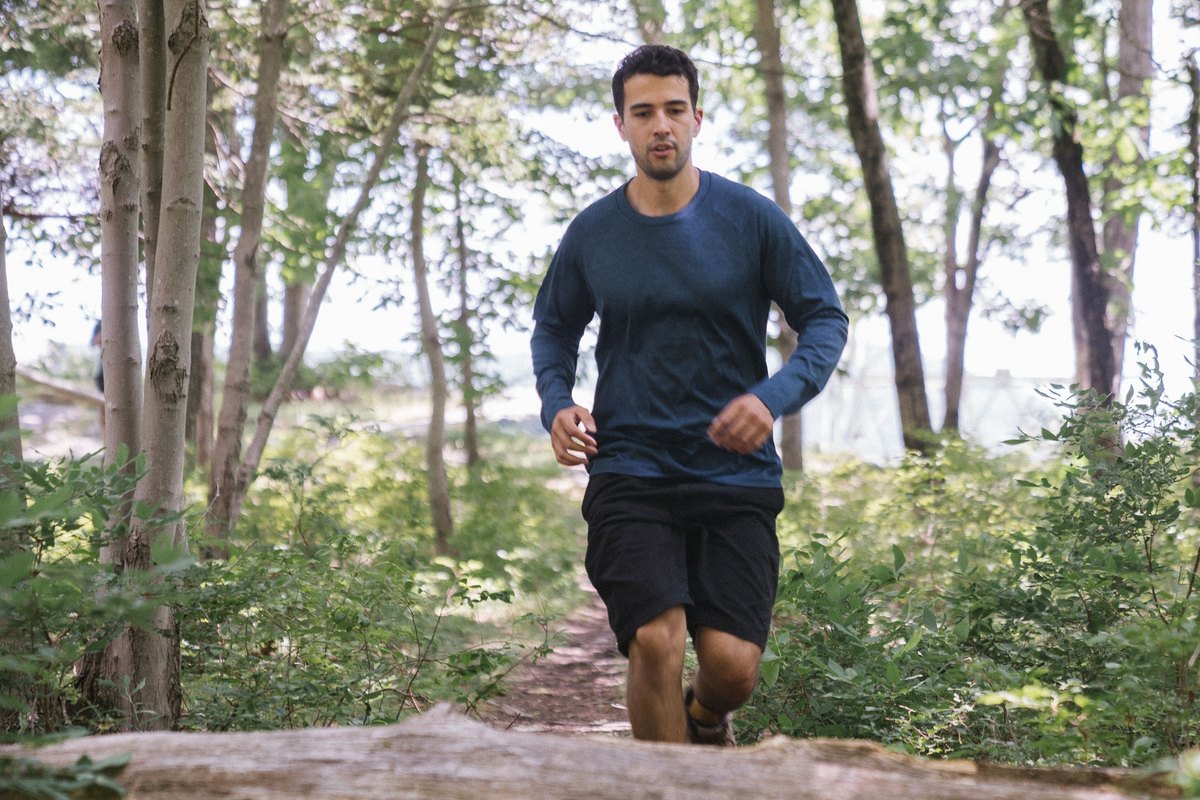 Man running along a forest trail toward a fallen log