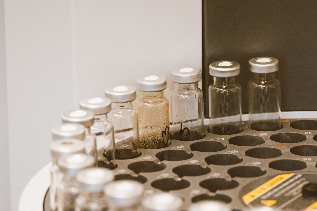Small glass vials with silver caps, one holding powder, on a laboratory tray