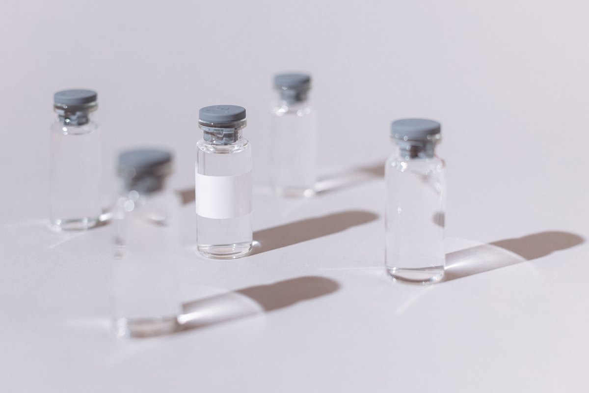 Small clear glass vials with gray stoppers on a pale surface