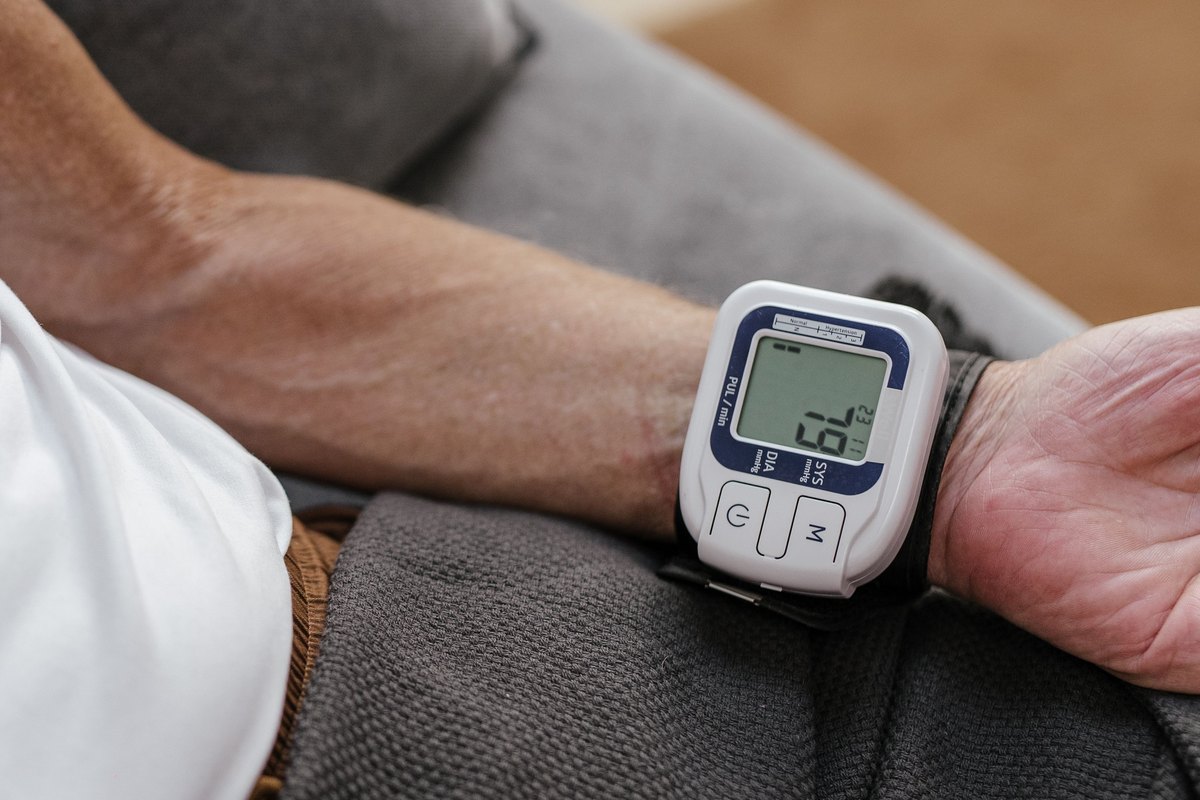 Man on a gray sofa wearing a wrist blood-pressure monitor